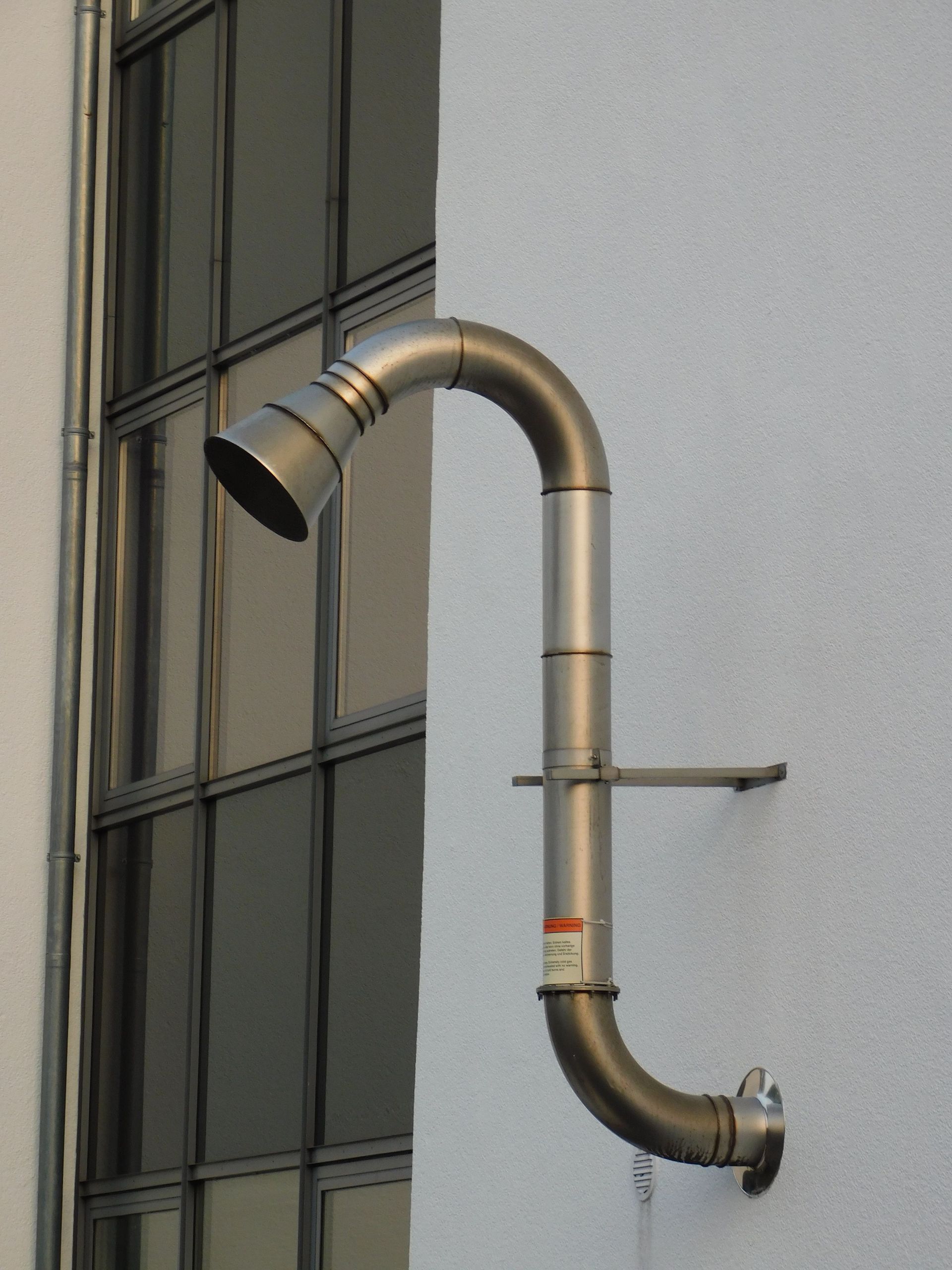 Steel vent pipe mounted on a modern building facade in Celle, Germany.